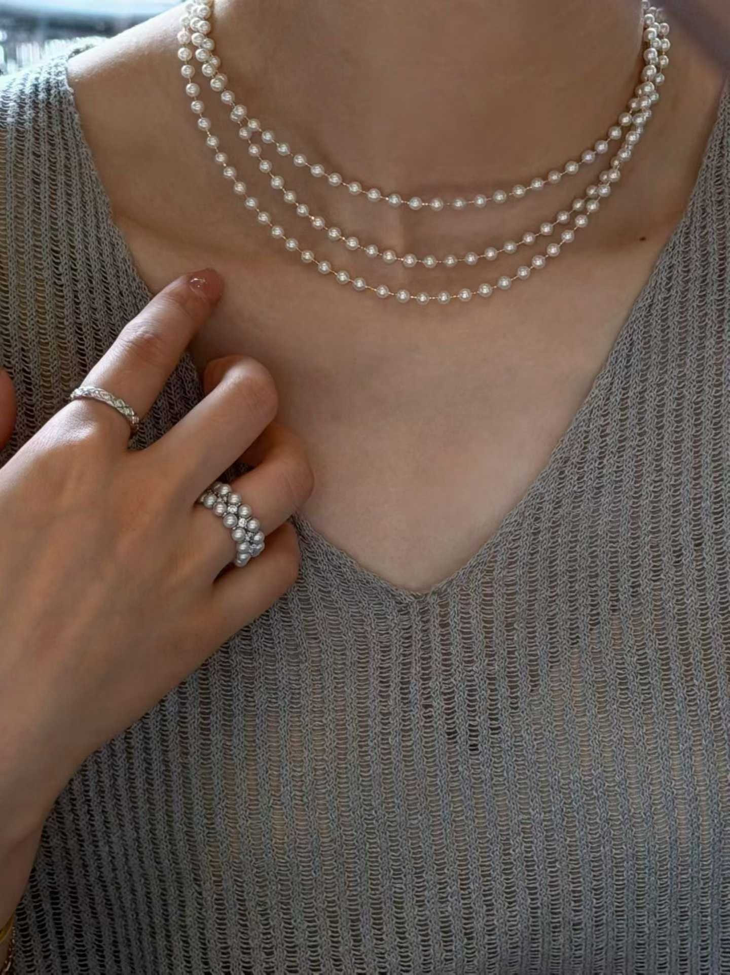 Layered pearl necklaces worn with a grey knit top